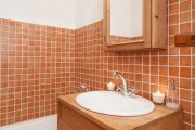 Tato koupelna je obložena rezavými kachlíky v podobném tónu jako dřevo
