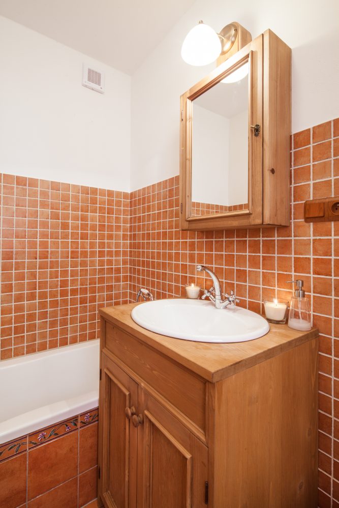 Tato koupelna je obložena rezavými kachlíky v podobném tónu jako dřevo