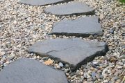 Do oblázků zapuštěné větší ploché kameny – šlapáky – mohou nahradit klasický dlážděný chodník. Foto: Shutterstock