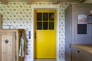Žluté posuvné dveře mezi vstupní halou a kuchyní tvoří barevně zajímavý kontrast k převažujícím bílým či béžovým odstínům