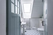 Převažující bílou v podkrovní koupelně zajímavě doplňuje tyrkysová barva dveří